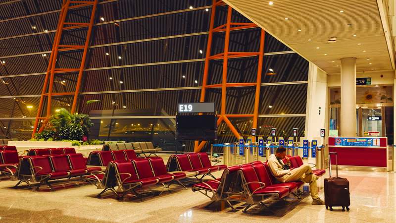Traveler at airport luggage carousel looking stressed with delayed baggage signs